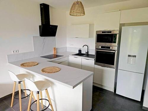 - une cuisine avec un comptoir avec des tabourets et une cuisinière dans l'établissement Charmant t2 avec terrasse, à Corte