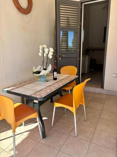 Una mesa con sillas y un jarrón de flores encima. en Agriturismo Antico Vigneto, en Otranto