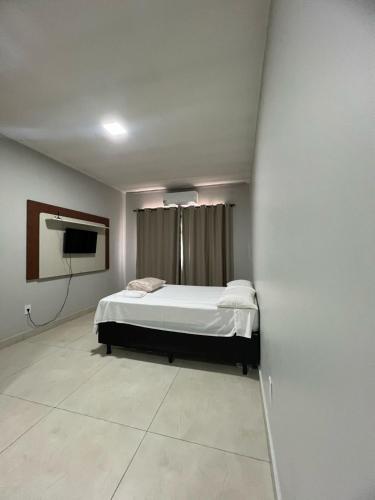 パスト・デ・ミナスにあるApartamento 112 - Suíte com ar condicionadoのベッドと薄型テレビのある寝室
