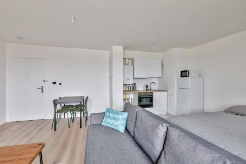 un salon avec un canapé et une table et une cuisine dans l'établissement Grand studio à Rosny, à Rosny-sous-Bois