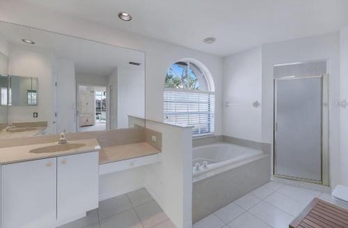 Stunning Sunsets and Water Views في جزيرة ماركو: حمام أبيض مع حوض ومغسلة ودش