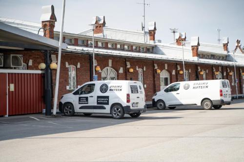 two white vans parked in front of a brick building at Hiisi Hotel Turku Seaport in Turku