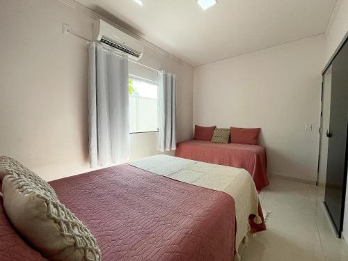 a bedroom with two beds and a window at Casa Privativa de 3 Quartos com Piscina com Aquecimento Solar a 800m das Praias de Taperapuan, Ar Condicionado, WiFi 110Mbps, Churrasqueira, Garagem para 02 Carros in Porto Seguro