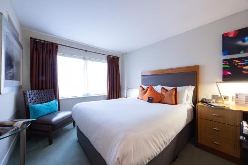 a hotel room with a large bed and a chair at Bermondsey Square Hotel - A Bespoke Hotel in London