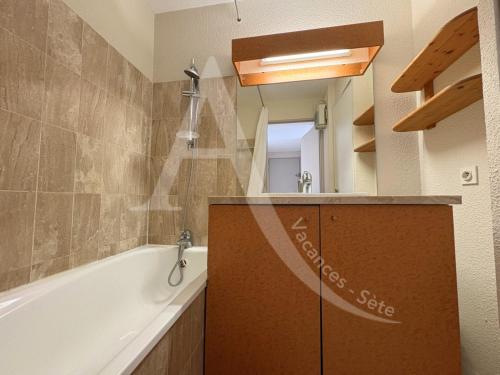 une salle de bain avec une baignoire, un lavabo et un miroir dans l'établissement 2 CHAMBRES, LARGE TERRASSE 1ERE LIGNE MER, PISCINE, à Sète