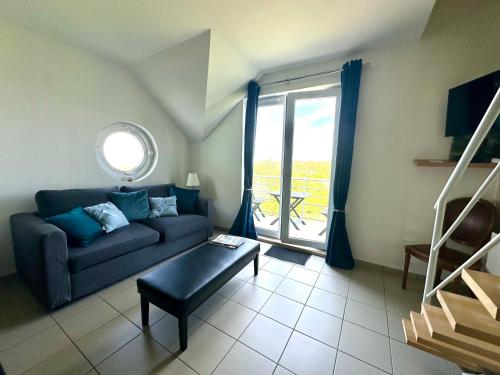 un salon avec un canapé bleu et une fenêtre dans l'établissement Entre mer et dunes d'Opale - duplex vue mer, à Wimereux
