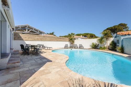 - une piscine avec des tables et des chaises à côté d'une maison dans l'établissement L'Avocette, au Bois-Plage-en-Ré