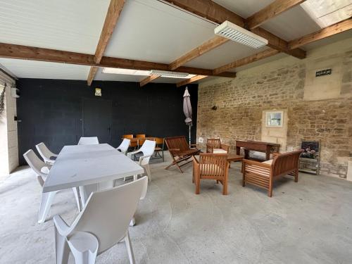 une pièce avec une table, des chaises et une cheminée dans l'établissement L Ancre Maison séjour spacieux lumineux avec jardin et extérieur aménagé terrain de petanque proche Omaha beach, Grandcamp Maisy et pointe du Hoc, à Saint-Pierre-du-Mont