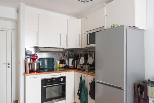  La cuisine est équipée de placards blancs et d'un réfrigérateur. dans l'établissement Apartment of 26 m2 near the park of Belleville, à Paris