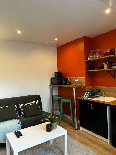 un salon avec un canapé et une cuisine dans l'établissement La Maison au fond du jardin - proche centre ville, au Mans