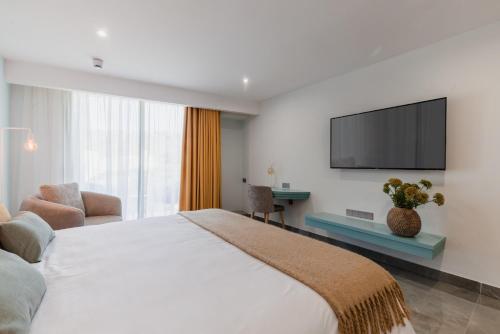 1 dormitorio con 1 cama grande y TV en la pared en Reef Hotel & Spa, en Marsalforn