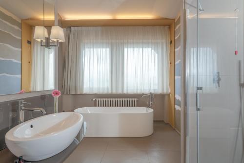 a white bathroom with a tub and a sink at Titano Suites in San Marino