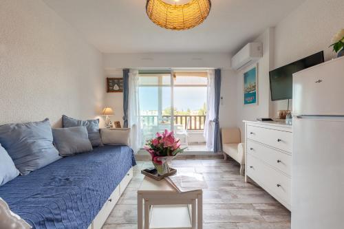 un salon avec un canapé bleu et un balcon dans l'établissement Sanary Sur Mer,Soleil Et Douceur Il, à Sanary-sur-Mer