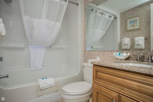 a bathroom with a toilet and a tub and a sink at Beach Cove Resort in Myrtle Beach