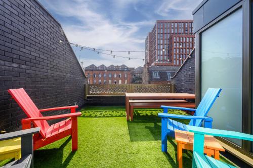 a balcony with colorful chairs and a table and bench at Luxury Canal St Villa with Free Parking in Manchester