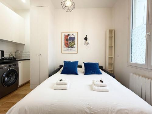 une chambre avec un grand lit blanc avec des oreillers bleus dans l'établissement Charming studio for 2 guest - 2min walk from metro, à Paris