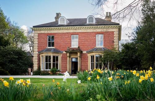 a woman standing in front of a brick house with flowers at Charming 18th Century property in Topcliffe Station