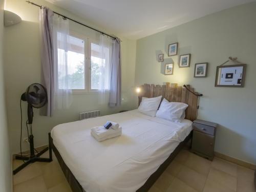 une chambre avec un grand lit blanc avec une fenêtre dans l'établissement Les Terrasses de Cavald'Or - T2 with pool, au Lavandou