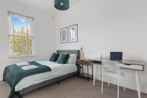 a bedroom with a bed and a desk with a computer at The Turnpike Residence - Free Parking in London