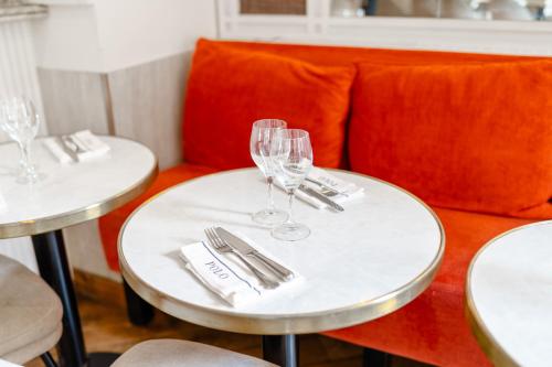 due tavoli con bicchieri da vino e tovaglioli e un divano di HotelHome Paris 16 a Parigi