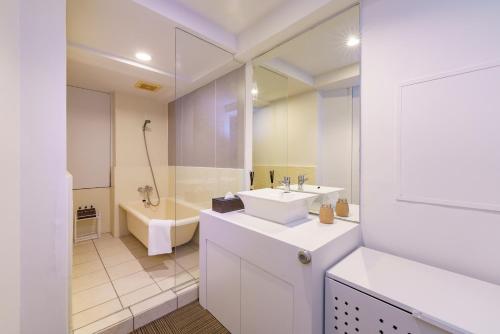 a white bathroom with a sink and a tub and a toilet at feel Akihabara STAY in Tokyo