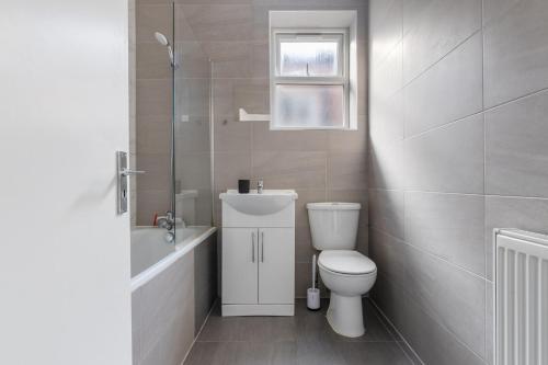 a bathroom with a toilet and a sink and a tub at The Turnpike Residence - Free Parking in London