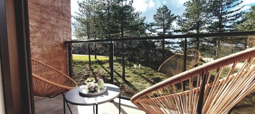Un balcón con dos sillas de mimbre y una mesa. en FOREST SIDE Apartmani, en Divčibare
