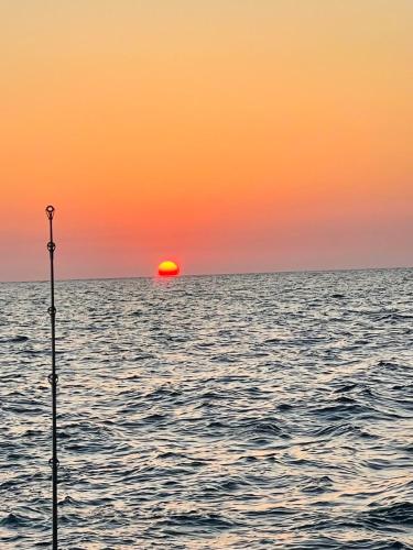 a sunset over the ocean with a pole in the water at Keys Livin - Yacht Rental in Key West