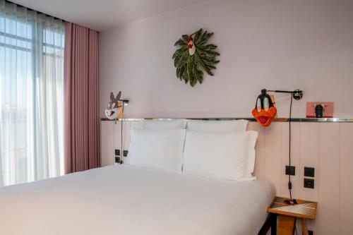 a bedroom with a large white bed and a window at Mama Shelter Lisboa in Lisbon