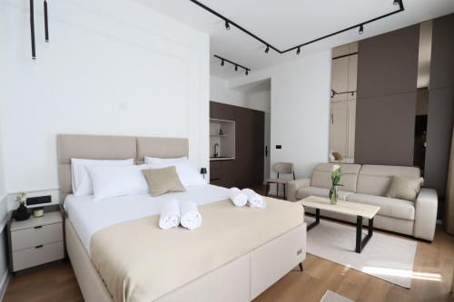 Un dormitorio con una gran cama blanca y una sala de estar. en Din Luxury Apartments, en Sarajevo