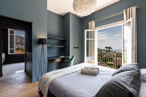 - une chambre avec des murs bleus et un lit avec une grande fenêtre dans l'établissement HSAUVAN - Villa Design Swimming Pool Sea View, à Saint-Jean-Cap-Ferrat