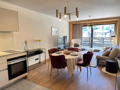 une cuisine et un salon avec une table et des chaises dans l'établissement Appartement lumineux au cœur des Gets avec balcon et parking - FR-1-623-222, aux Gets