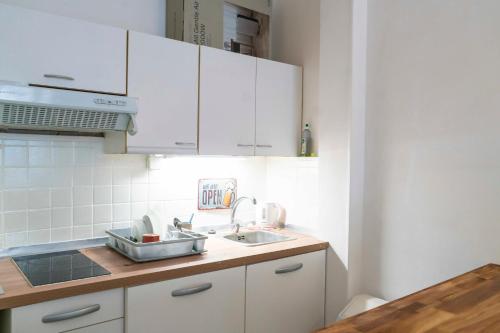 une cuisine avec des armoires blanches et un évier dans l'établissement Charming studio with view near Montmartre, à Paris