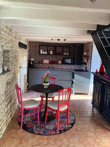 une cuisine avec une table, quatre chaises et un comptoir dans l'établissement La petite Chapelle, à LʼIsle-sur-Serein