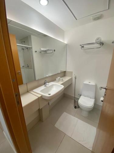 a bathroom with a sink and a toilet and a mirror at Flat Hilton Garden - Belo Horizonte 1017 in Belo Horizonte