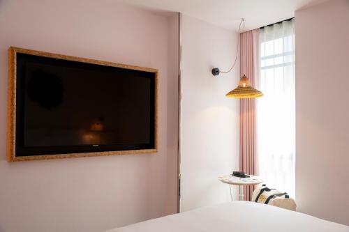a flat screen tv hanging on a wall next to a bed at Mama Shelter Lisboa in Lisbon