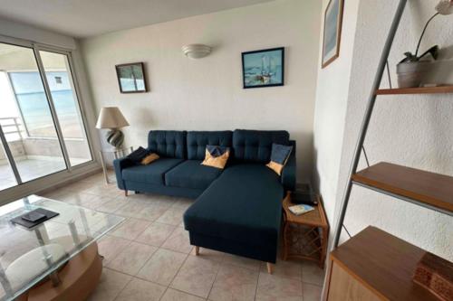 un salon avec un canapé bleu et une table en verre dans l'établissement Bright seafront apartment, à Palavas-les-Flots