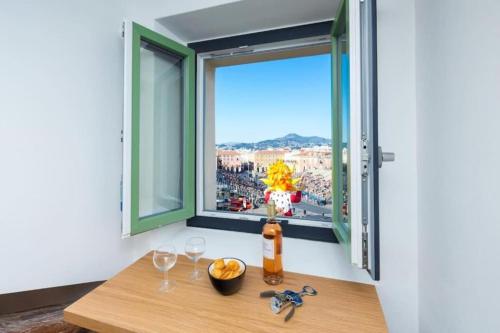 - une table avec deux verres à vin et une fenêtre dans l'établissement MASSENA 44 - Stunning studio on Masséna Square, à Nice