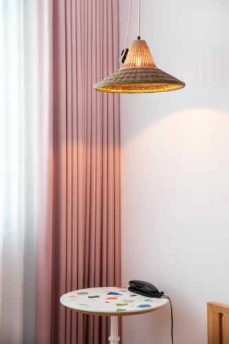 a lamp and a table in front of a curtain at Mama Shelter Lisboa in Lisbon