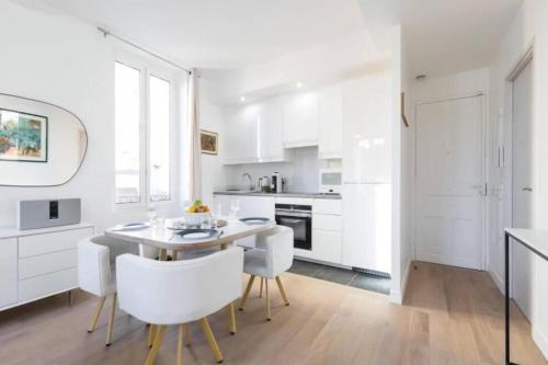 une cuisine avec des armoires blanches et une table et des chaises dans l'établissement MOULIN - Stunning 1 bedroom Apt on the Port, à Nice