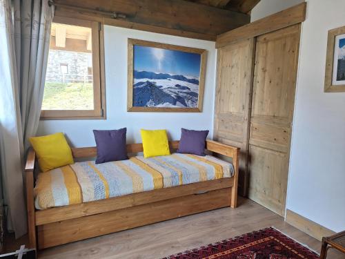 a room with a couch with yellow and purple pillows at Les 7 laux immobilier chalet F in Prapoutel