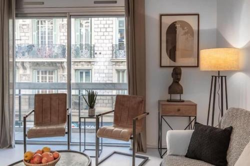 un salon avec un canapé et des chaises et une grande fenêtre dans l'établissement ROSSINI - Central and cosy with AC, à Nice