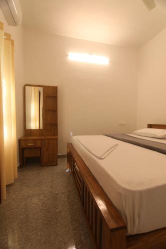 a bedroom with a bed and a dresser and a mirror at Periyar Homes Plantation Stay in Thekkady