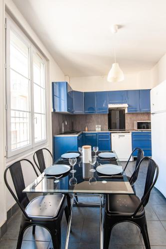 une cuisine avec une table, des chaises et des armoires bleues dans l'établissement Appartement Ancien - 4 chambres - Centre ville Poitiers, à Poitiers