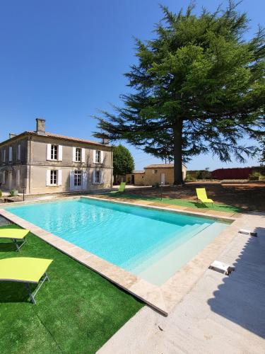 une grande piscine avec des chaises et un arbre dans l'établissement La suite du Grand Cèdre, à Lussac