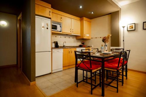 Il comprend une cuisine équipée d'une table avec des chaises et d'un réfrigérateur blanc. dans l'établissement Inmocyma Antigua Casa Chuanina, bajo-Benasque, à Benasque
