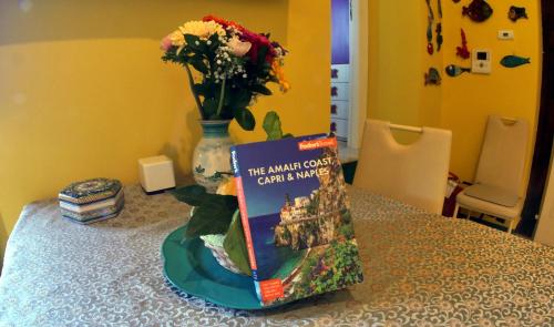 a book sitting on a table next to a vase with flowers at Casa Angelica in Ravello