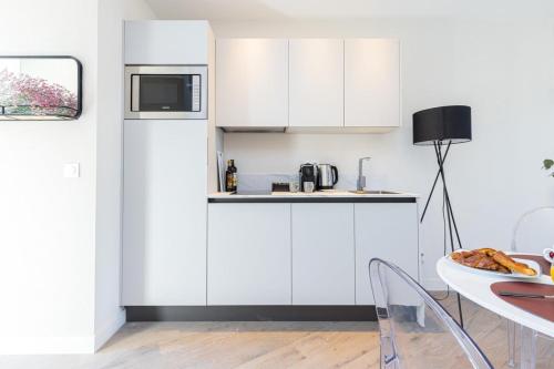 une cuisine avec des armoires blanches et une table dans l'établissement BAVASTRO - The Port - New apartment 2 rooms, à Nice