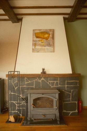 a stone fireplace in a living room with a painting at Le Chalet in Bouillon