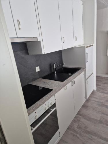 a kitchen with white cabinets and a sink at dala Hotel & Apartments in Leukerbad